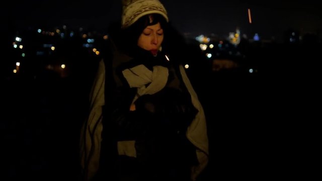 Hobo young girl frizzing at cold city night at bonfire lowlight close-up 