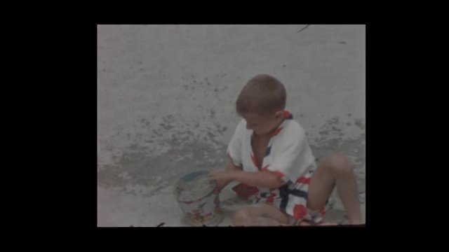 1956 Cute Young blonde boy digs in sand at beach