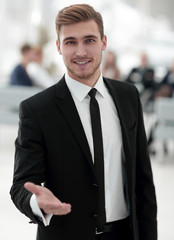 confident young businessman holds out his hand for greeting