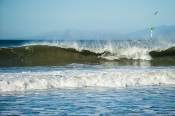 Only disembodied feet of California surfer show as offshore winds create large and hollow tube waves covering his surfboard.