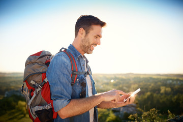 Joyful man using phone to check map during hiking trip