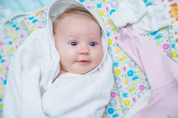 Baby in white towel after bathing.