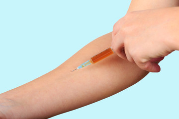 Close-up of hand, giving vaccination to patient using a syringe with brown drugs.  Sterile injection in the upper arm.