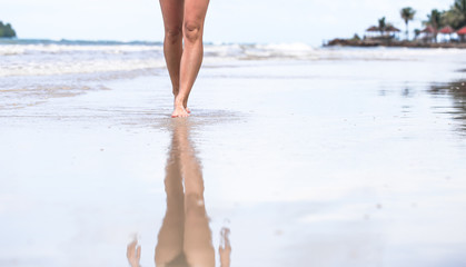 beautiful female legs on the beach with water splashing