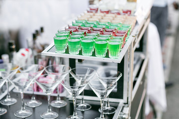 row line of different colored alcoholic cocktails on a party. wedding day or birthday