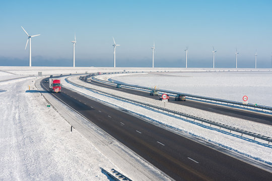 Dutch winter landscape with highway along wind turbines against a blue sky