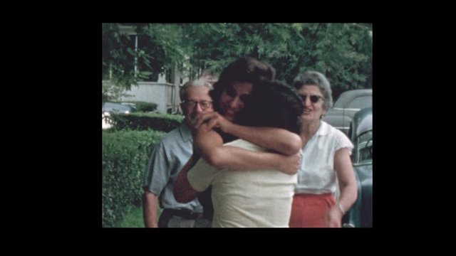 1956 Family hugs and kisses goodbye in front of vintage antique cars