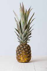 Closeup of pineapple on white wooden table and on light blue background.