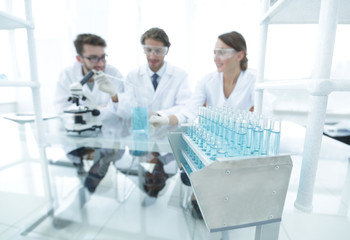 background image of scientists studying blue liquid in a flask