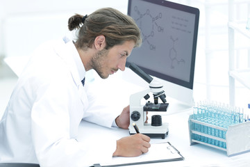 Obraz premium Laboratory worker sitting by table with microscope