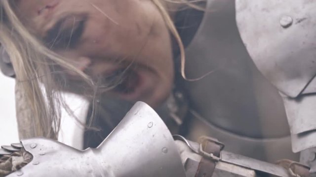 The blonde in knightly armor bends over the sword and screams from grief