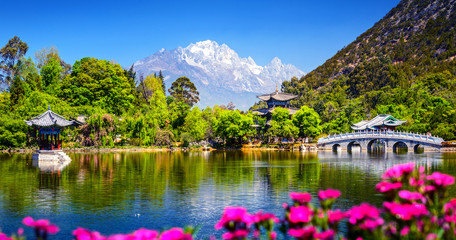 Black Dragon Pool and Jade Dragon Snow Mountain. It's a famous pond in the scenic Jade Spring Park (Yu Quan Park) located at the foot of Elephant Hill, old Town of Lijiang in Yunnan, China. - obrazy, fototapety, plakaty