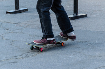Fototapeta na wymiar Legs of the skater on skateboard in skatepark