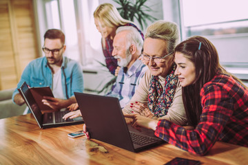 Young volunteers help senior people on the computer
