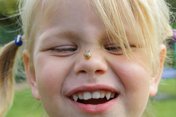 Ein kleines Mädchen lässt eine kleine Schnecke über seine Nase kriechen