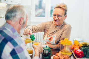 Elderly couple in the kitchen preparing breakfast