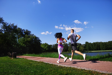 Woman and man running in the Park along the path near the lake.