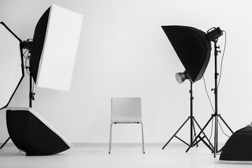 Interior of modern photo studio with chair and professional equipment