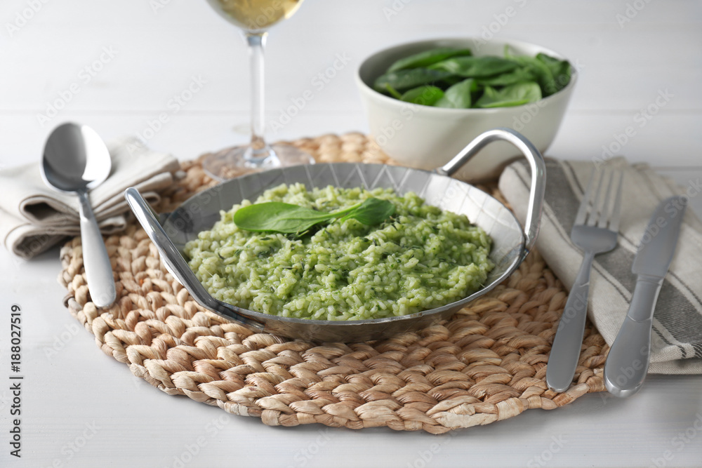 Sticker dish with delicious spinach risotto on wooden table