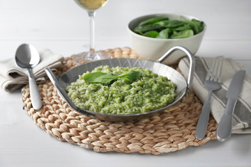 Dish with delicious spinach risotto on wooden table