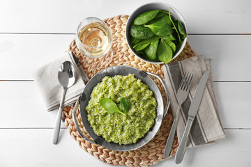 Dish with delicious spinach risotto on wooden table
