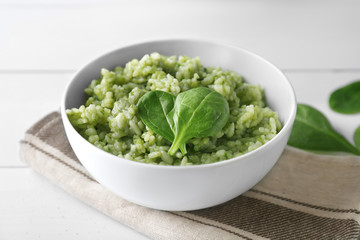 Dish with delicious spinach risotto on wooden table