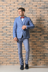 Handsome man in elegant suit near brick wall