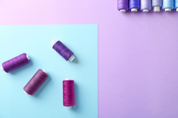 Set of sewing threads on color background, top view