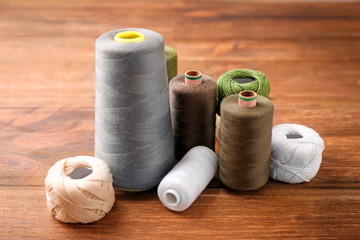Sewing threads with clews on wooden background