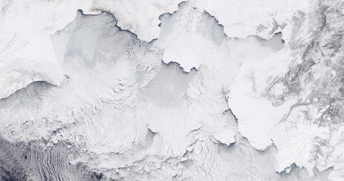 Very high-altitude overflight aerial of ice sheets and sea ice, northern Bering Sea coast. Clip loops and is reversible. Elements of this image furnished by USGS/NASA Landsat