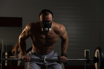 Fototapeta na wymiar Bodybuilder Exercising Push-Ups On Barbell In Elevation Mask