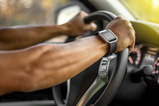 Man who wearing smart watch is driving vehicle while working or going to somewhere with the flare from the outside.