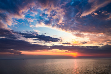 Naklejka na ściany i meble Colorful sunset over calm sea in summer with sun beam