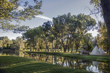 trees and teepee reflecting into lake