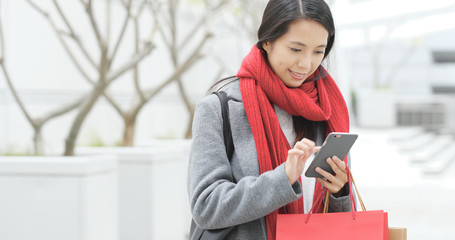 Shopping woman using mobile phone and holding paper bag