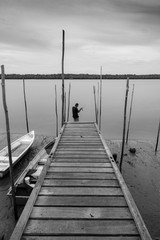 Black and white of fishing alone in a lonely river in dramatic evening.