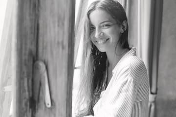 Fototapeta premium Excited happy mixed race female with dark hair having eyes full of happiness while looking out of bedroom window, noticing her boyfriend who is making great surprise to her, singing serenade on street