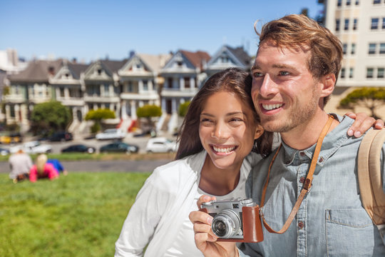 San Francisco Painted Ladies houses people tourists on America summer trip holidays taking photos, Young multiethnic couple asian woman, caucasian man.