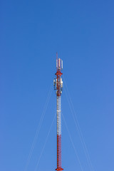 Red and white Telecommunication tower in a day of clear blue sky. Telephone pole