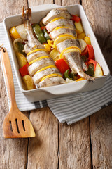 Atlantic cod fish baked with pepper, tomatoes, onions and lemon in a baking dish close up. vertical