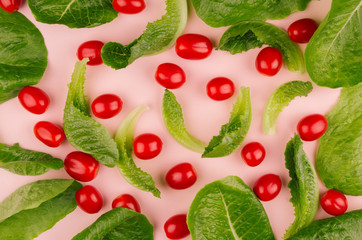 Fresh leafy greens and cherry tomatoes on pink background.
