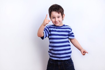 Little lovely boy pointing on something, studio shoot on white. Emotions, childhood concept