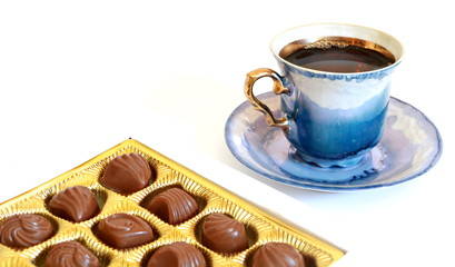 Porcelain vintage pattern cup of hot black tea on saucer and box chocolate candy. Isolated. White background