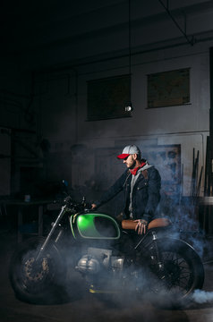 Man posing with his custom motorbike in garage