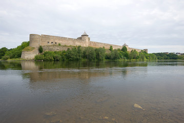 Naklejka na ściany i meble Panorama of the Ivangorod Fortress and the Narva River on a cloudy August day. Ivangorod, Russia