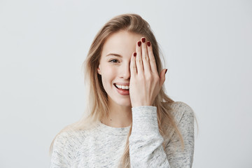 Happy smiling female with attractive appearance and blonde hair wearing loose sweater showing her...