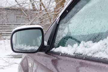 Snow covered SUV side mirror closeup. Cars in winter