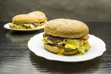 Beef burger on a white plate on a wooden background.
