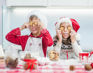 Happy kids having fun at home, holds cookie  before his eyes like in glasses