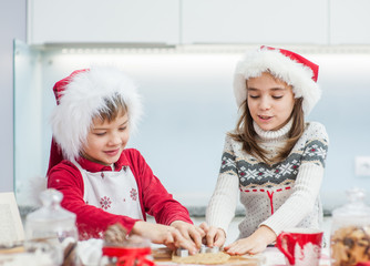 Brother and sister cooking Christmas cookies at home